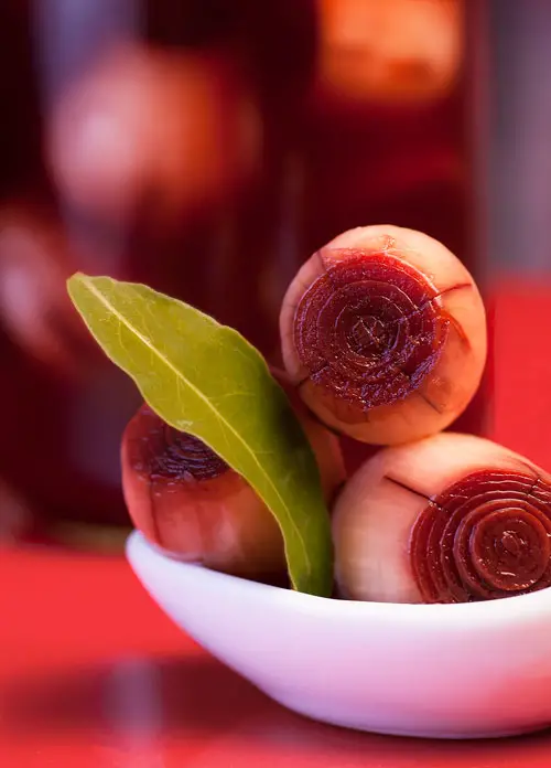 Pickled Onions with a glass jar behind.