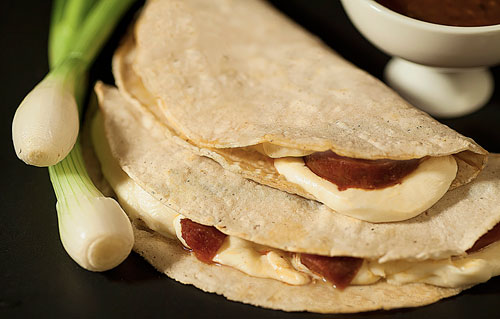 Chorizo Quesadilla next to a spring onion and salsa