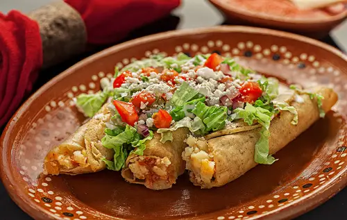 Tacos Dorados de Chorizo con Papas cubiertos con muchos ingredientes frescos